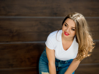 Young, attractive girl in a white t-shirt and jeans on a brown background.