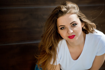 Fototapeta premium Portrait of a charming girl in a white t-shirt on a brown background. Close-up.