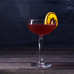 Alcohol cocktail drink with slice of an orange on the rustic background