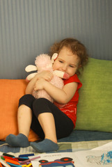 Pretty little girl hugging a toy sheep