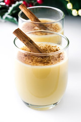 Homemade eggnog with cinnamon isolated on white background. Typical Christmas dessert.
