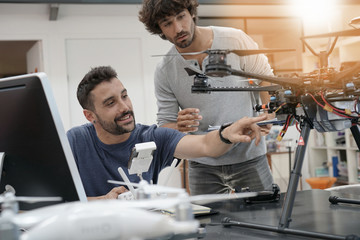 Engineer and technician working together on drone in office - obrazy, fototapety, plakaty