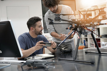 Engineer and technician working together on drone in office