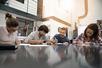 Young people sitting around table signing documents