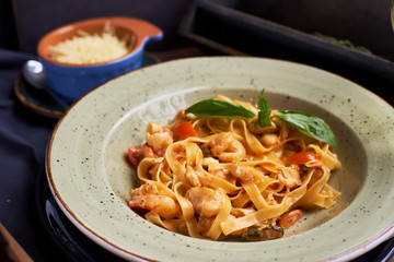 Seafood pasta. Tagliatelle with prawns and spices in tomato-cream sauce. Glass of white wine.
