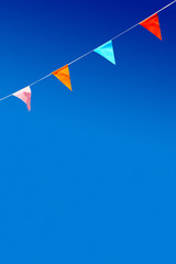Bunting with four multicolor triangular party flags against blue sky.