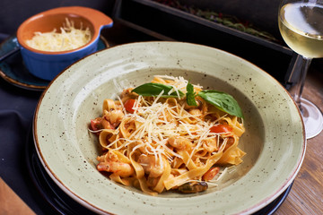 Seafood pasta. Tagliatelle with prawns and spices in tomato-cream sauce. Glass of white wine.