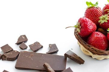 Broken chocolate, strawberries in a wicker basket