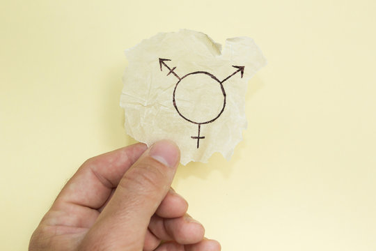 Transgender symbol in hand on a yellow background. Close-up.
