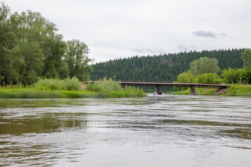 old iron bridge over the river Ufa with the broken icebreaker