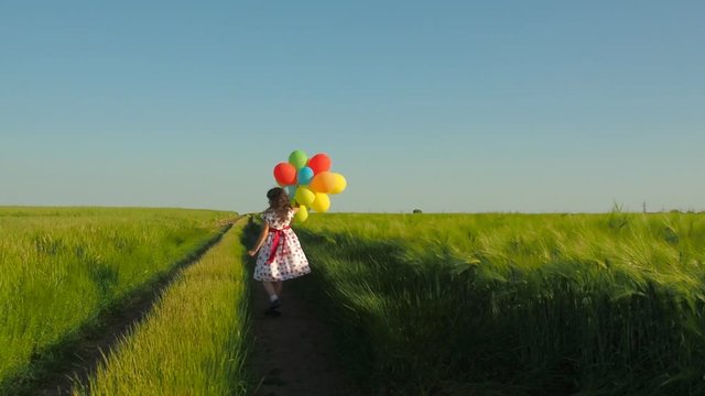 Child with balloons in the field. Little girl with balloons on nature.