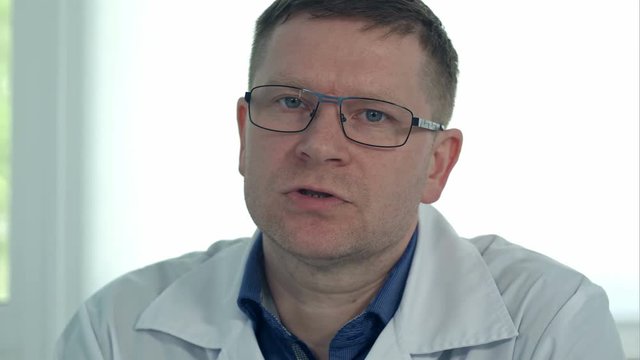Male doctor in glasses talking to the camera