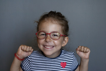 Happy little girl wearing red glasses against myopia. Development of mental abilities at an early...