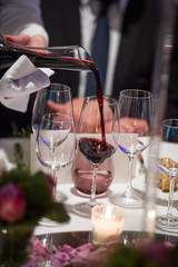Sommelier pouring wine into glass from mixing bowl, luxury diner