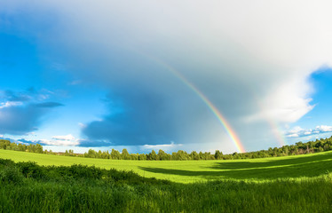 Colorful rainbow over the green field.
