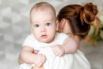 Mother with her newborn baby. Mother is holding her little baby girl. Photo with the effect of sunlight, soft natural light, with selective focus. Baby on mom's shoulder.