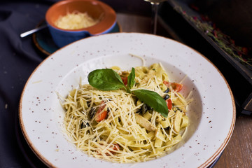 Traditional italian pasta served on table in rustic style. Tagliatelle with chicken slices, olives and cheese.