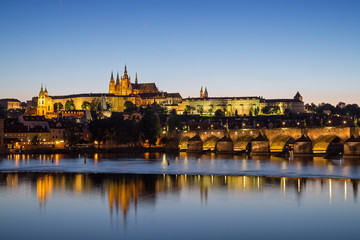 Obraz premium View of the lit Prague (Hradcany) Castle, Charles Bridge (Karluv most) and their reflections on the Vltava River in Prague, Czech Republic, at night.