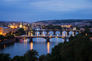 Fototapeta na wymiar Lit buildings and bridges over Vltava River in Prague, Czech Republic, viewed slightly from above at dusk.