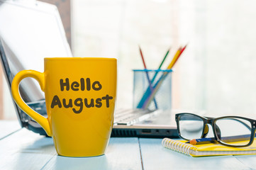 Hello August - inscription at yellow morning coffee or tea cup at business office background. Summer month, Calendar concept © bychykhin