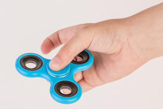 Male hand holding baby, holding a popular toy. A boy is playing with a blue spinner.