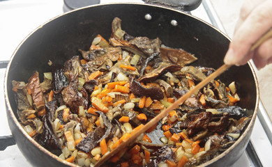Mushrooms fried on the pan with carrot and onion