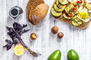 Vegetarian breakfast. Sandwiches with avocado, fried eggs and paprika on wooden table background top view