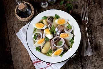 Salad from light-salted herring, boiled potatoes, eggs and onions with olive oil and lemon juice. Rustic style.