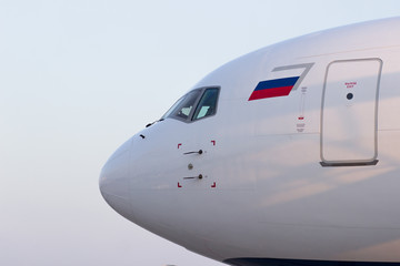 The nose of the aircraft in the light of the sunset with the Russian flag, the view from the side to the pilot's seat and the emergency exit door