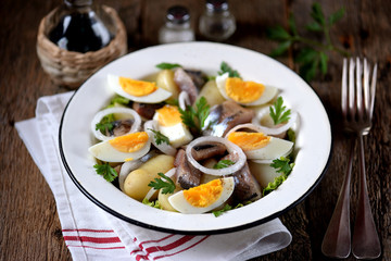 Fototapeta na wymiar Salad from light-salted herring, boiled potatoes, eggs and onions with olive oil and lemon juice. Rustic style.