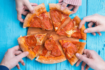 Picture of pizza on table. People take pieces