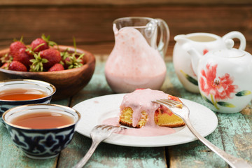 Yummy homemade cake with fresh strawberries, tea and cream sause in glass jar