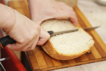 Woman cutting a bread on the wooden desk