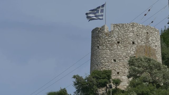 Greece medieval tower and flag on Ithaka island, in Greece.
