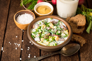 Okroshka. Traditional Russian summer cold yogurt soup in bowl on wooden background.