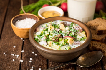Okroshka. Traditional Russian summer cold yogurt soup in bowl on wooden background.