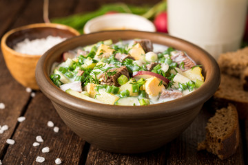 Okroshka. Traditional Russian summer cold yogurt soup in bowl on wooden background.