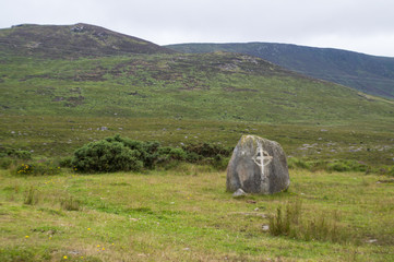 Rock in a wild landscape with a celtic cross on it