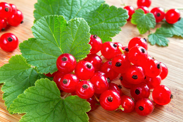 Juicy ripe raw red currant berries and leaves on a wooden background.The concept of gardening and harvesting