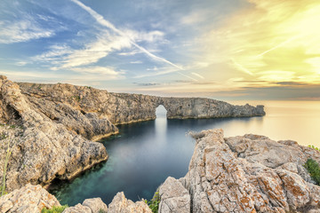 The rock formation bridge located on the west coast of Menorca Spain offers one of the most extraordinary sunsets - obrazy, fototapety, plakaty