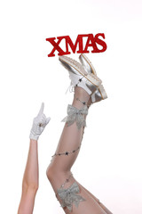A pair of woman's legs are stretched out high in front of a white background. Christmas and winter...