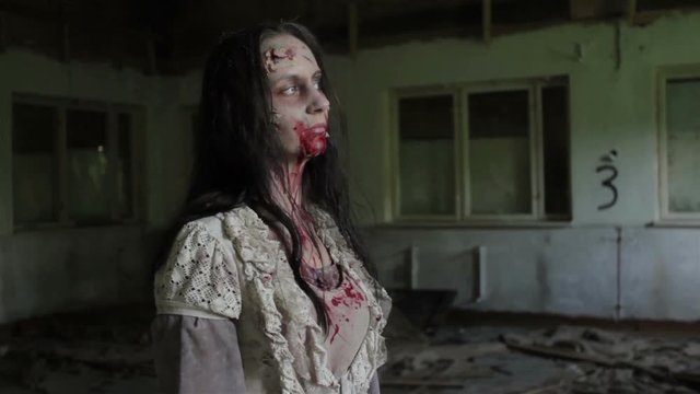A zombie girl stands and looks out the window from an abandoned building.