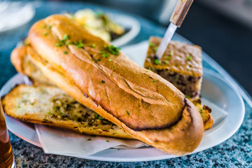 Macro closeup of large pieces of garlic bread in restaurant on plate with knife