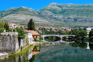 Fototapeta na wymiar Reflections of the Kameni Most bridge and buildings in the Trebišnjica River of Trebinje, Bosnia Herzegovina