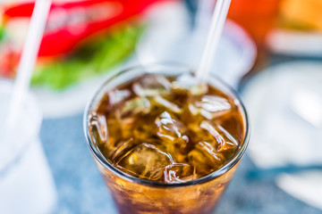 Macro closeup of iced tea or coke with cubes of ice and straw in glass