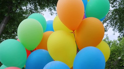 colored helium balloons, festive colorful air balloons associated bundle, swaying in light wind blow, holiday accessories on nature, fastened balloons into bundle, slow motion