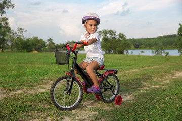 The child riding a bicycle. The kid in a helmet riding a bike in the park. Beautiful baby.