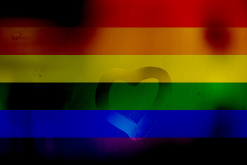 Fototapeta premium Lgbt flag rainbow heart shape on rainbow background. Heart painted on wet glass, against background of the colors symbols of homosexual people. Love and family for lesbian, gay, bisexual, transsexual