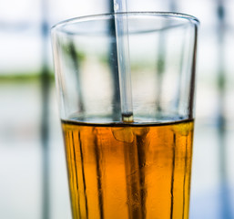 Macro closeup of melted iced tea and straw in glass