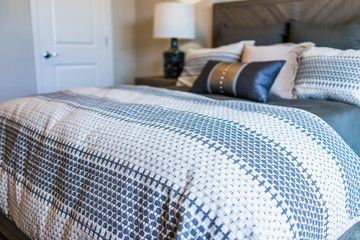 Closeup of new bed comforter with decorative pillows in bedroom